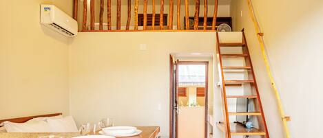 Un coin repas avec une table en bois dressée pour quatre personnes, un escalier avec une rampe en bois et un luminaire au plafond.