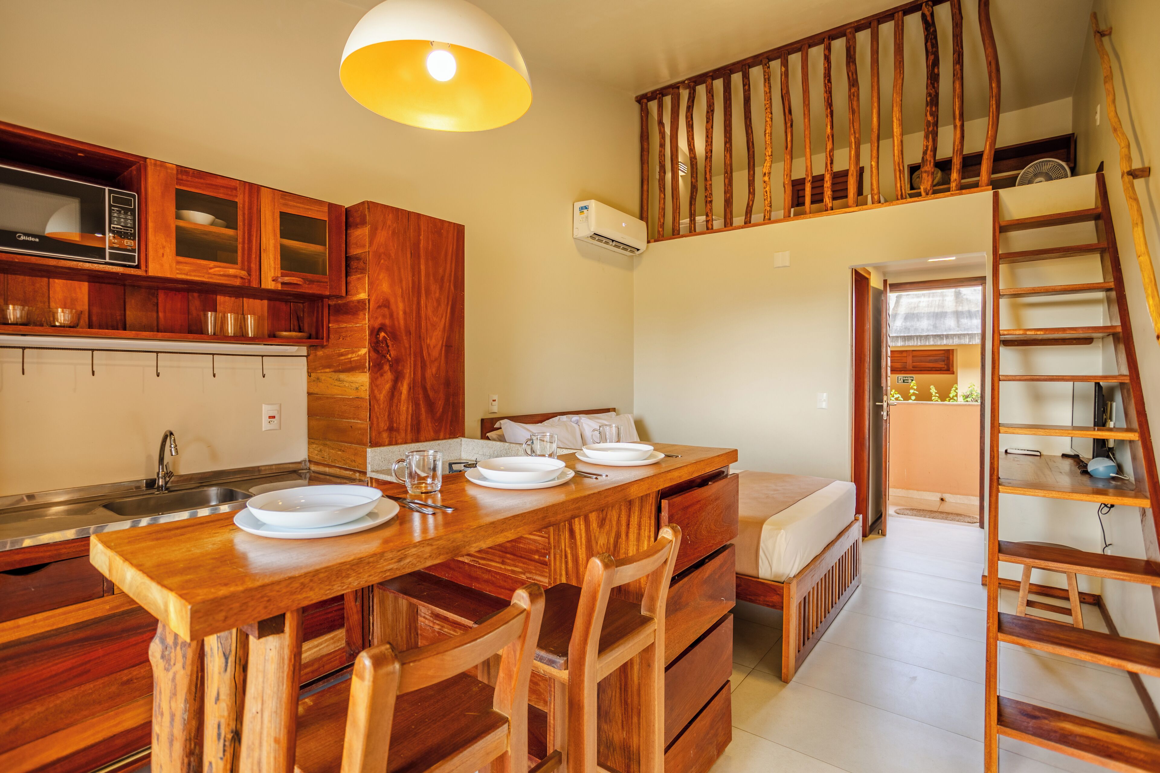 A wooden kitchen with a dining table set, a staircase, and a view of the outdoors.
