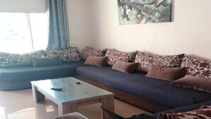 Una sala de estar con un sofá, cojines estampados, una mesa de centro y una computadora portátil.