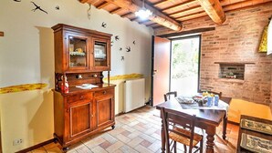 Una cucina rustica con un armadietto in legno, un tavolo da pranzo con sedie, un muro in mattoni e una finestra.