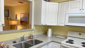 A kitchen with white cabinets, a double sink, a microwave, and an oven. - Desirable Ground Floor Condo in a Gated Community with Pool & Fitness Center! (Saint Simons Island)