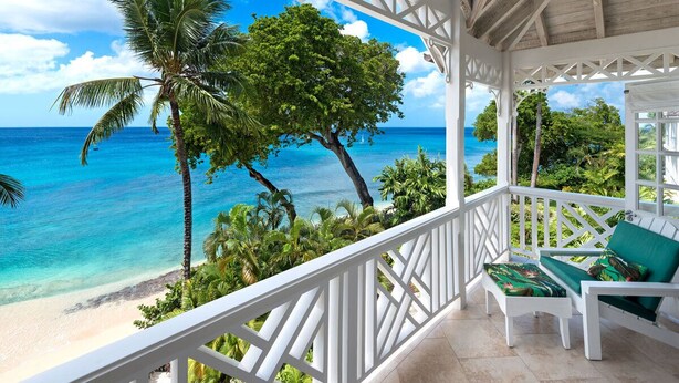 A balcony with a view of a beach and ocean, white railings, and green cushioned seating. - Beachfront Bliss with Plunge Pool - Seashells (Paynes Bay)