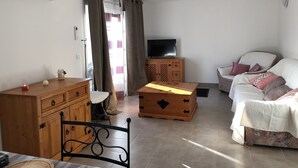 Ein Wohnzimmer mit einer Holzkabine, einem Fernseher auf einem Holzständer, einem Sofa und einem Sessel.
