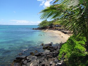 Uma praia com águas turquesa cristalinas, costa rochosa e vegetação exuberante.