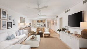 Ein geräumiges Wohnzimmer mit einem weißen Sofa, einem Couchtisch und einem Essbereich mit Stühlen und Tisch.