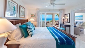 A hotel room with a bed, a desk, a chair, and a view of the ocean. - Beachfront Condo with Plunge Pool - Reeds House 10 (Reeds Bay)
