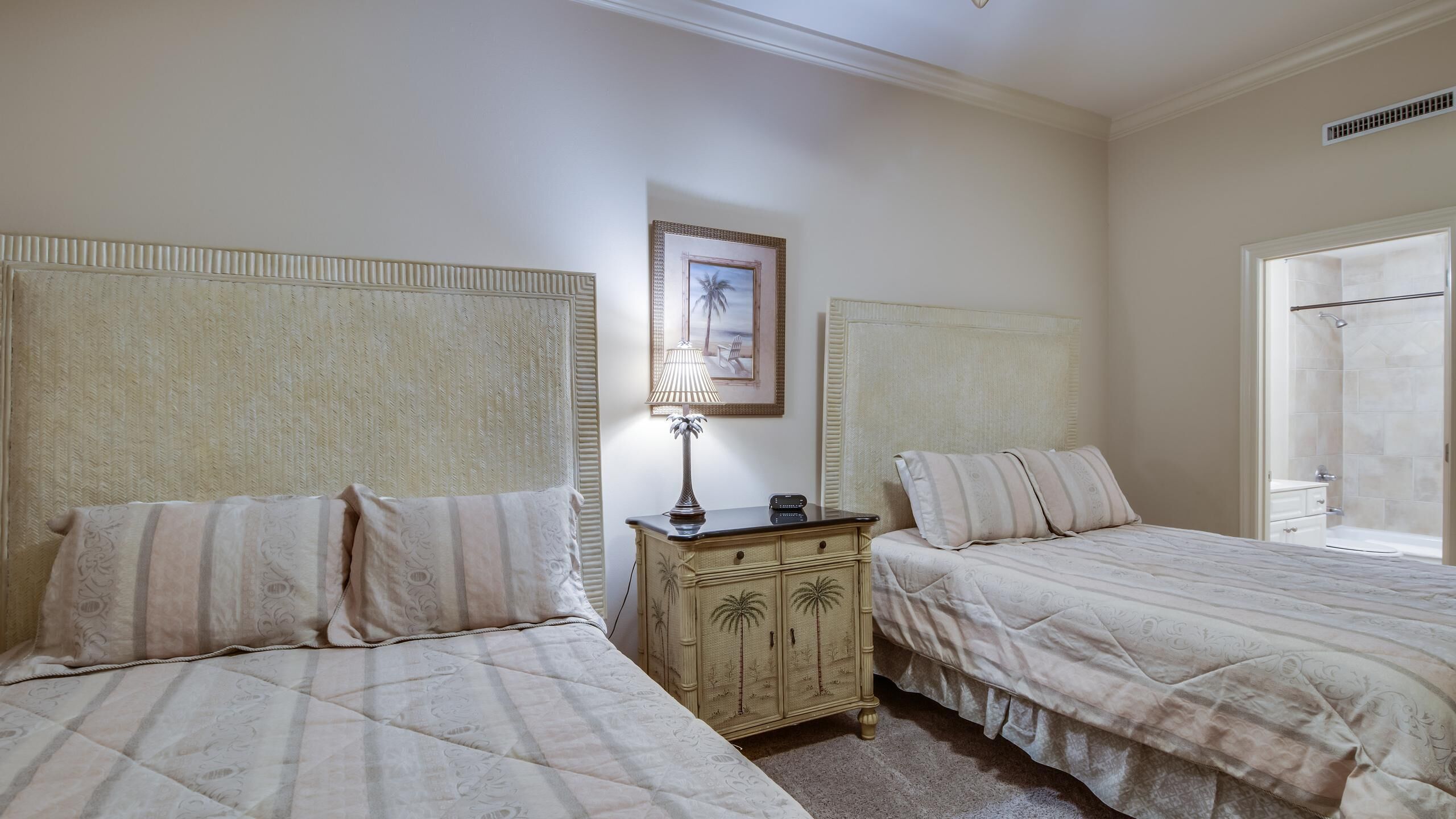 Un dormitorio con dos camas, una mesita de noche, una lámpara y un cuadro en la pared.