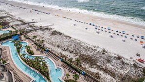 A beach resort with a swimming pool, beach umbrellas, and a lifeguard tower. - Breathtaking Gulf Views – Welcome to Phoenix West 1103! (Orange Beach)