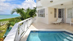 Ein Poolbereich mit Blick auf den Ozean, ein weißer Balkon mit einem Stuhl und ein gefliester Boden.
