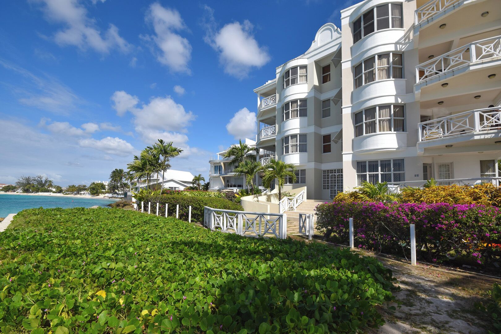 Un hotel de varios pisos con balcones, piscina y vista a la playa.