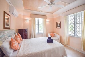 A hotel room with a bed, a chair, a dresser, and a ceiling fan. - Beachfront 2-Bed Condo with Plunge Pool - Indramer 1 (Worthing)