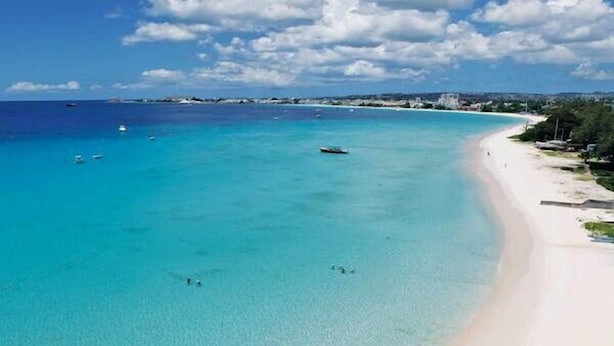 Ein Strand mit klarem türkisblauem Wasser, einem Sandstrand und einigen Booten.