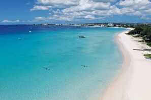 A beach with clear turquoise water, a sandy shore, and boats in the distance. - Beachfront 2-Bed Condo with Plunge Pool - Indramer 1 (Worthing)