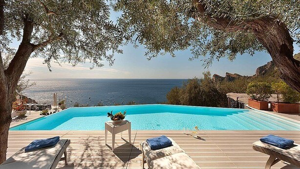 Un espace aménagé au bord de la piscine, avec des chaises longues et une vue sur la mer.
