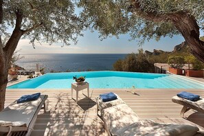 Zona de piscina con sillas de descanso y vista al mar.