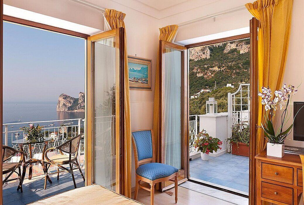 Ein Balkon mit Meerblick, einem Stuhl und einem Tisch mit Sitzgelegenheiten.
