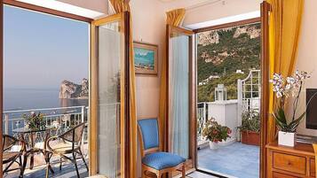 Un balcone con vista sul mare, una sedia e un tavolo con sedie.