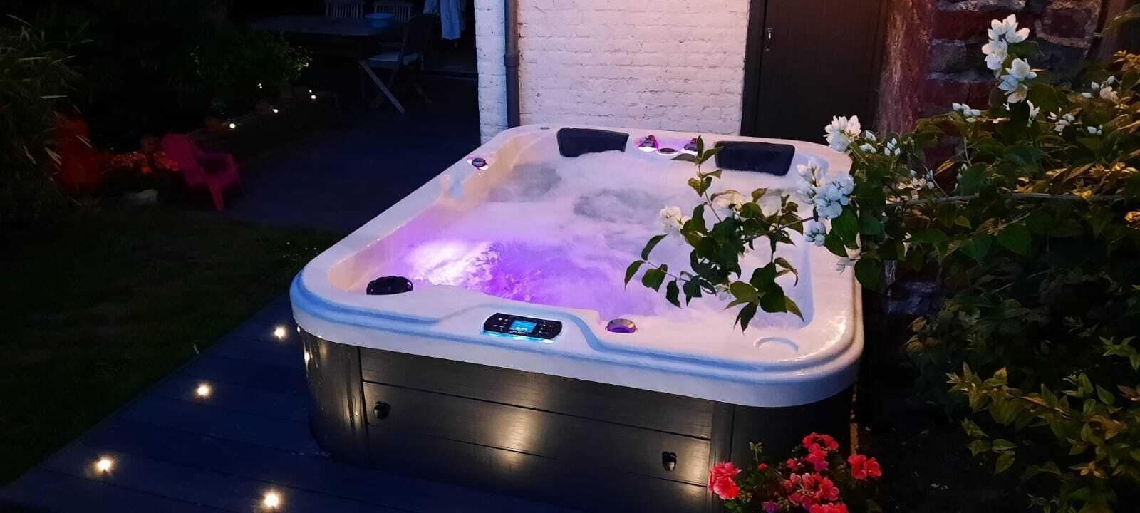 A hot tub with a control panel, surrounded by plants and flowers.