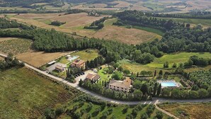 Vista aérea de una propiedad rural con varias construcciones, una piscina y campos escalonados.