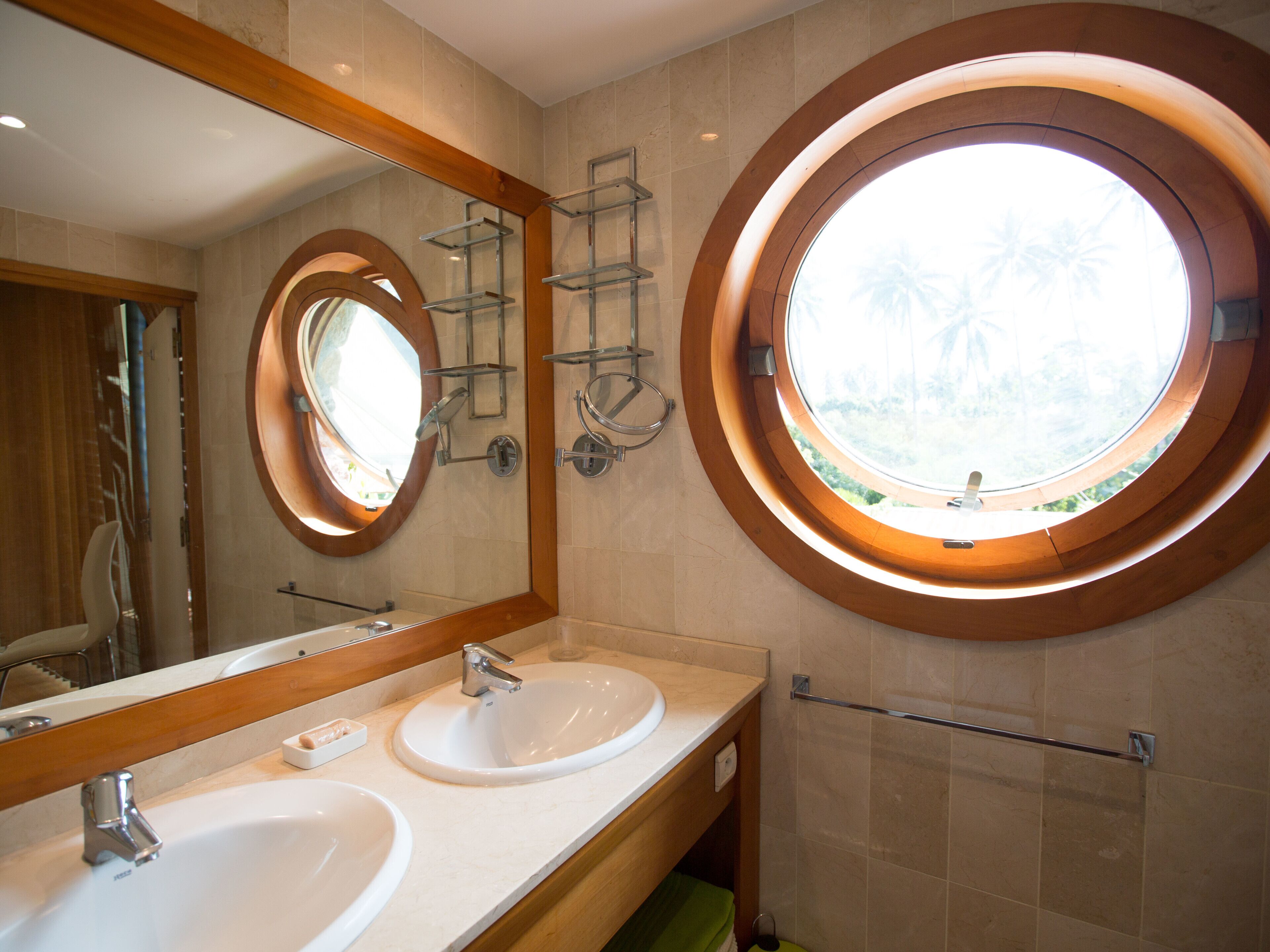 Ein Badezimmer mit zwei Waschbecken, einem großen Spiegel und einem runden Fenster.