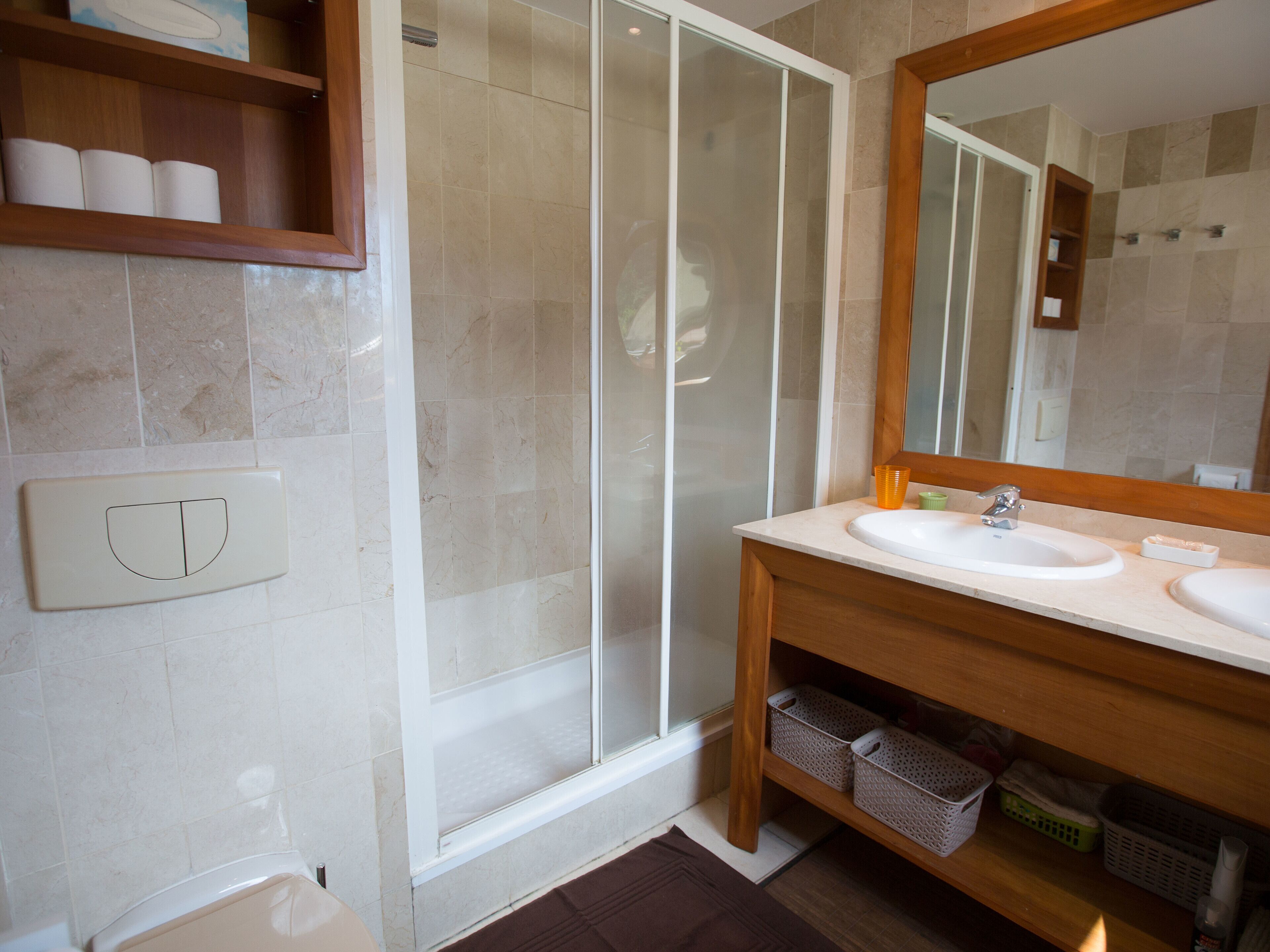 A bathroom with a shower, a sink, a mirror, and storage shelves.