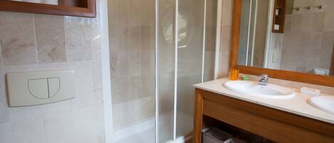 A bathroom with a shower, a sink, a mirror, and storage shelves.