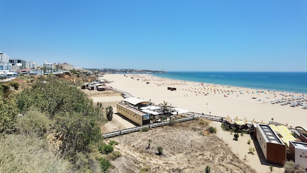 A beach with a row of beachside buildings, including a restaurant and a bus station.