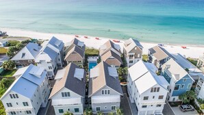 A coastal residential area with houses featuring gabled roofs and a beach in the background.
