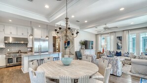A spacious kitchen with a central island, stainless steel appliances, and a chandelier.
