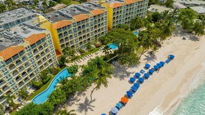 Een resort met een zwembad, strand en meerdere balkons.