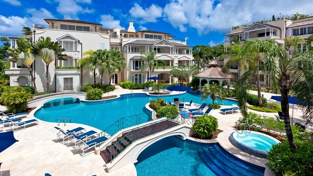 Et resort med en stor swimmingpool, liggestole og en velplejet have.