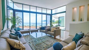 A modern living room with a large glass wall offering a view of the ocean. - Stunning Caribbean View with Entrance to Yal-ku Lagoon Akumal (Akumal)