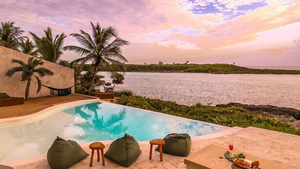 A poolside area with a view of the sea, seating, and a table with a drink and snacks. - Stunning Caribbean View with Entrance to Yal-ku Lagoon Akumal (Akumal)