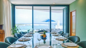 A dining area with a glass table, chairs, and a view of the ocean. - Stunning Caribbean View with Entrance to Yal-ku Lagoon Akumal (Akumal)