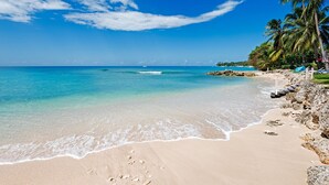 A beach with clear turquoise water, a sandy shore, and palm trees. - Private Beachfront Oasis - Reeds House 1 (3 bed) (Reeds Bay)