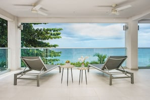 Relax on the balcony overlooking the water with comfortable lounge chairs and a small table.