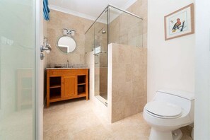 Une salle de bain moderne avec une douche à parois de verre, un meuble-lavabo en bois, un miroir rond et des toilettes blanches.