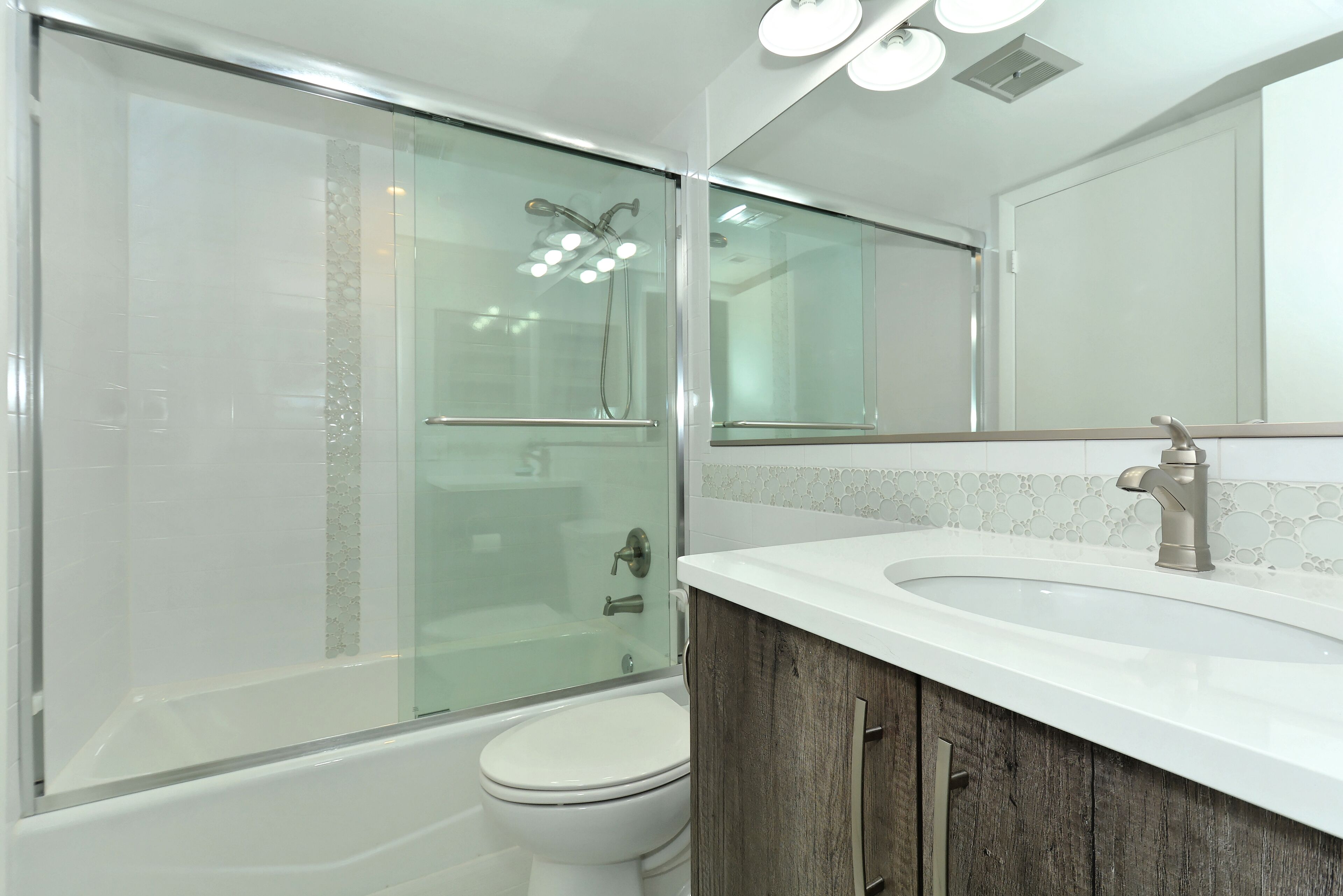 Une salle de bain moderne avec une douche à parois de verre, des toilettes blanches et un meuble-lavabo en bois avec un évier.