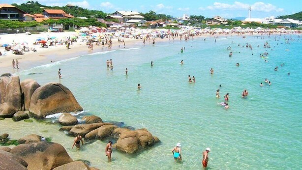 A crowded beach with clear water and large rocks. - Pousada da Lagoinha (Florianópolis)