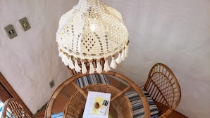 A round table with wicker chairs, a woven hanging light fixture, and a menu on the table. - Pousada da Lagoinha (Florianópolis)