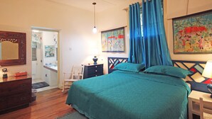 Un dormitorio con cama, escritorio, silla, cómoda, ventilador de techo y un cuadro en la pared.