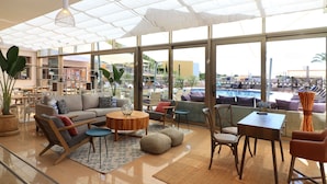 A spacious living area with a large window, a sofa, a coffee table, and a dining table with chairs.
