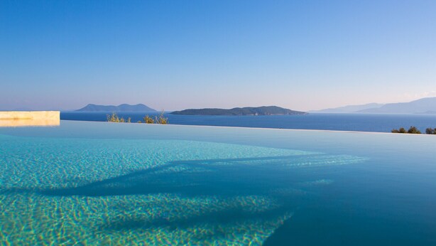 Ein Fernblick auf ferne Berge vom Infinity-Pool mit klarem, blauem Wasser.