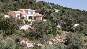 Eine Villa an einem Hang mit Stein Fundament, mehreren Etagen und einem gestuften Dach.