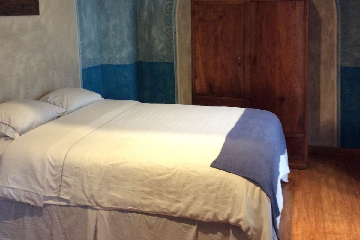 A bedroom with a bed, wooden wardrobe, and blue walls.