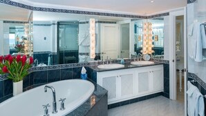 A modern bathroom with a large bathtub, two sinks, and a vanity with a mirror.