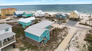 Une zone résidentielle côtière avec des maisons sur pilotis, une plage de sable et l’océan en toile de fond.