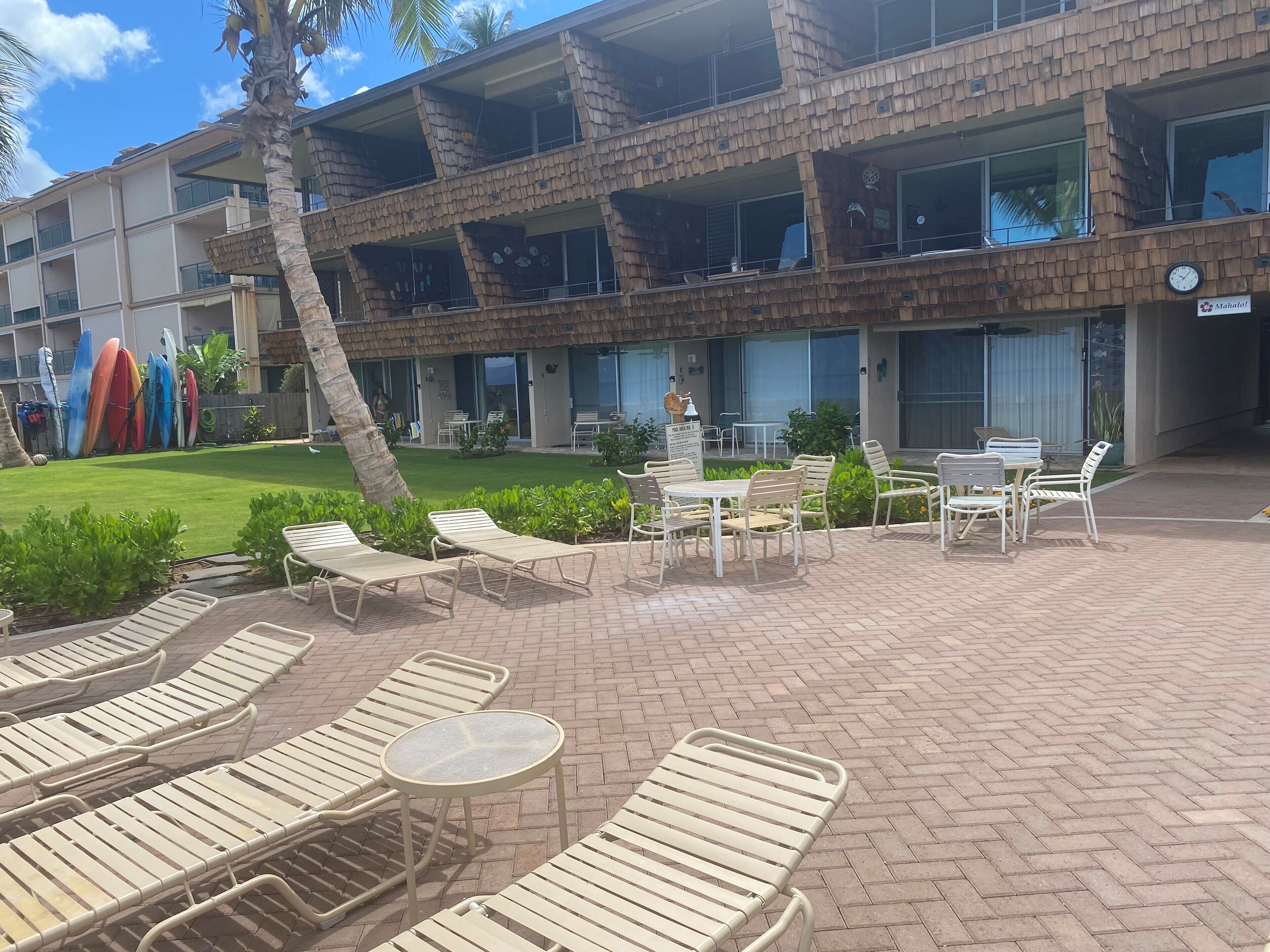 Ein Hotel mit Ziegelvorfront, Außenbereich mit Liegestühlen und Tischen sowie Blick auf den Pool.