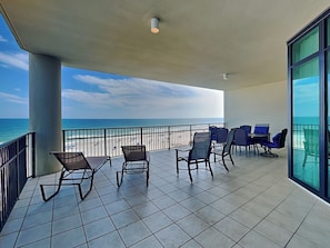 Un balcón con sillas y una mesa, con vistas a una playa y al océano.