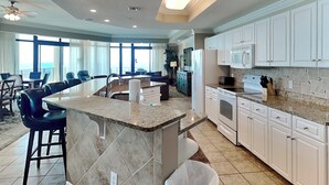 A spacious kitchen with white cabinets, a granite countertop, and a large island.